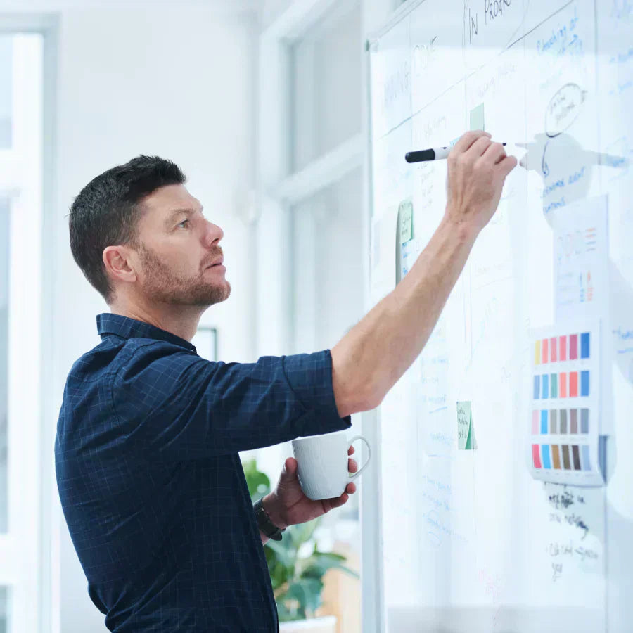 A professional writing on a whiteboard while wearing a black Plaud NotePin on his shirt collar.