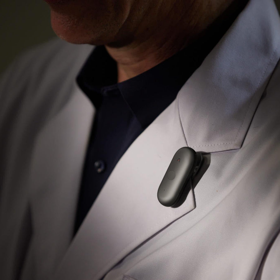Cosmic Gray Plaud NotePin S clipped to the lapel of a white lab coat.