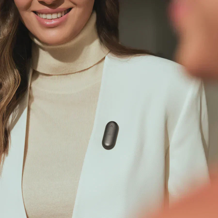 Black Plaud NotePin worn on a woman's white blazer lapel.