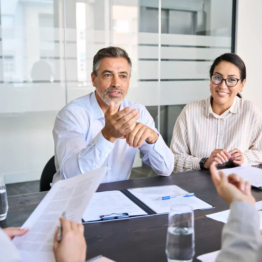 Professionals discussing documents during a business meeting in a bright office.