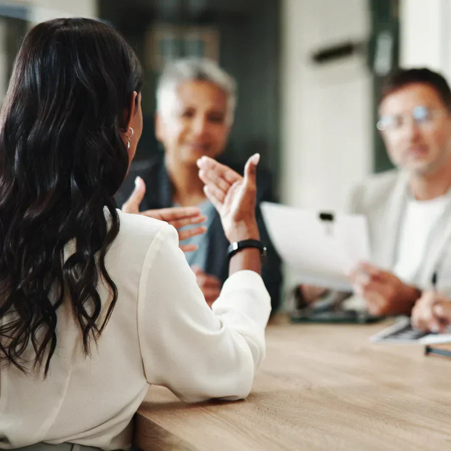 Woman wearing a black Plaud NotePin on her wrist while speaking in a business meeting.
