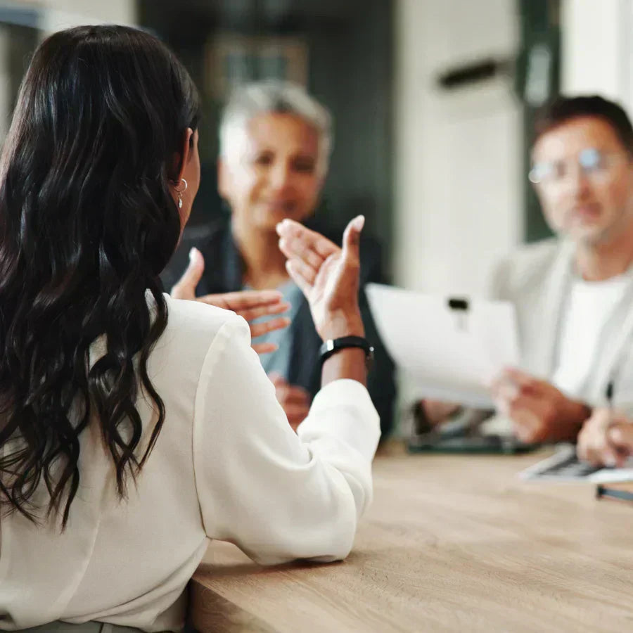 A woman gestures during a business meeting, representing a use case for a Plaud AI voice recorder.