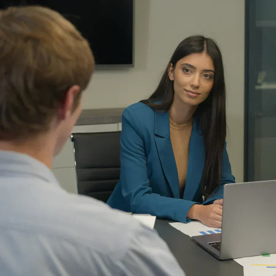 Woman in a blue blazer wearing a silver Plaud NotePin during a professional meeting with a colleague.