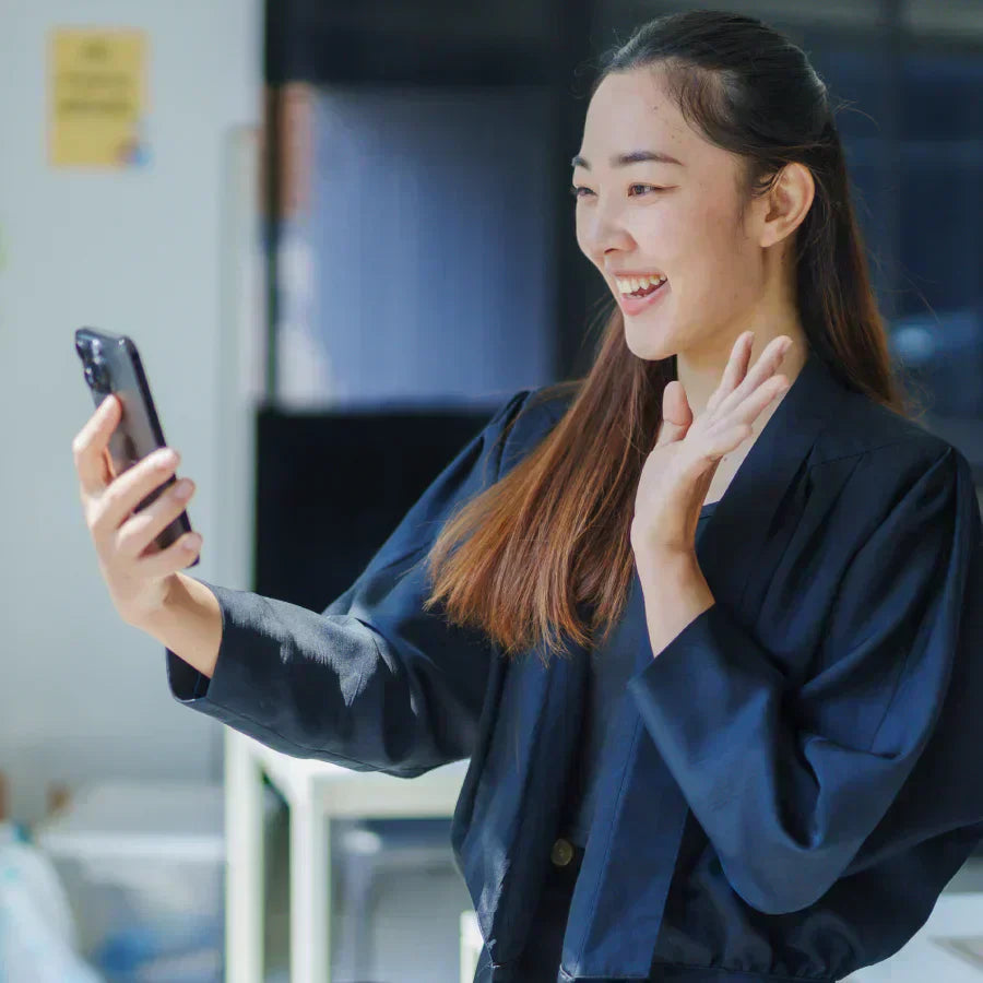 Smiling woman on a video call with a black Plaud Note AI voice recorder attached to her phone.