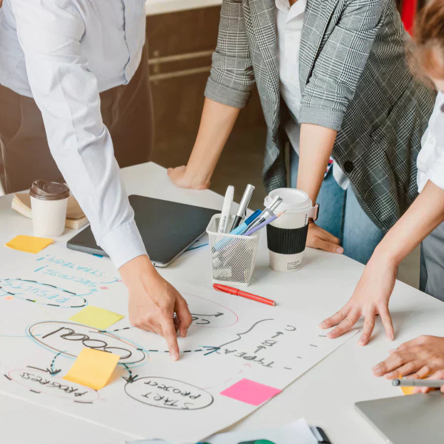 A professional team collaborating on a project plan with sticky notes and diagrams during a brainstorming session.