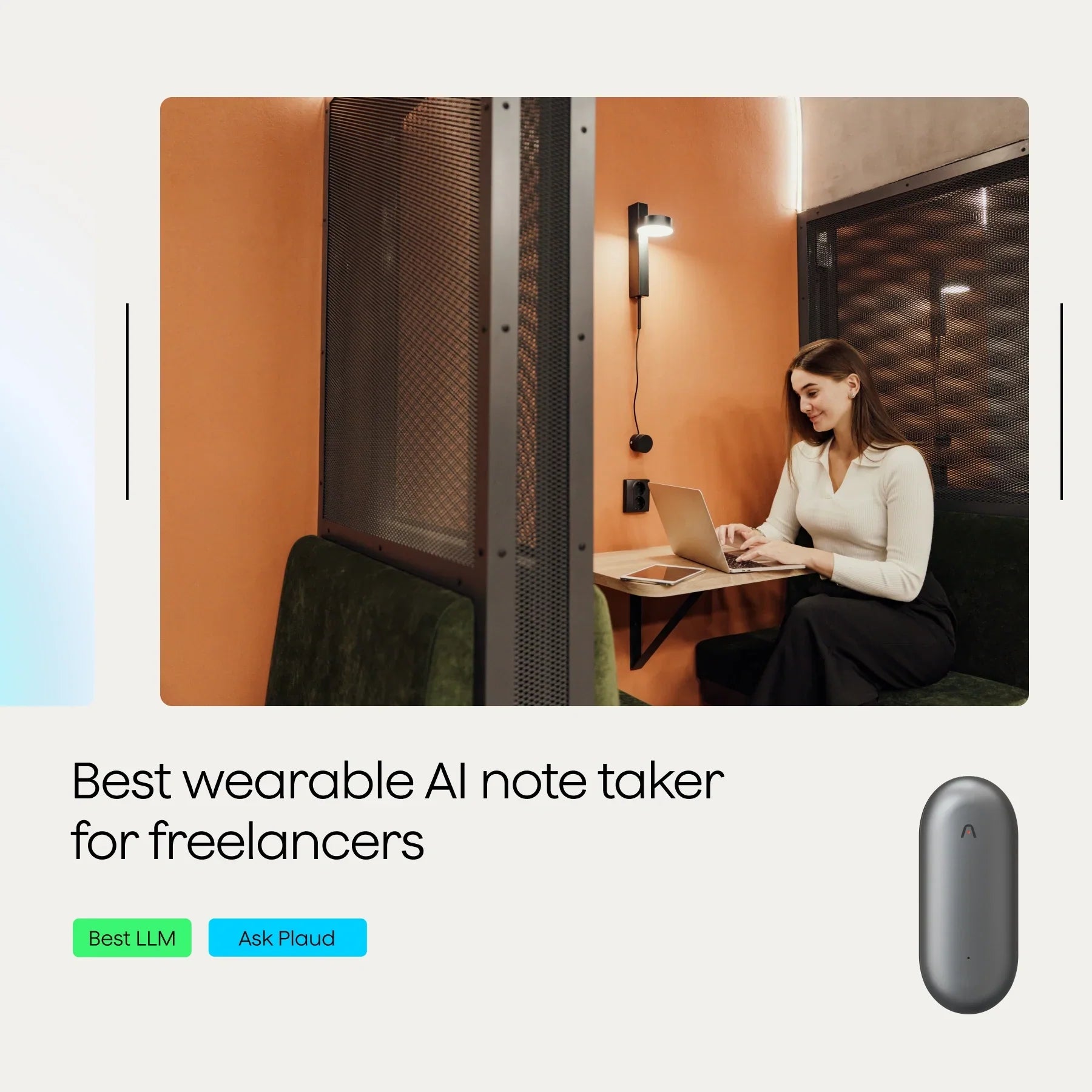 A woman working on a laptop at a café, surrounded by a partition and warm-colored walls.