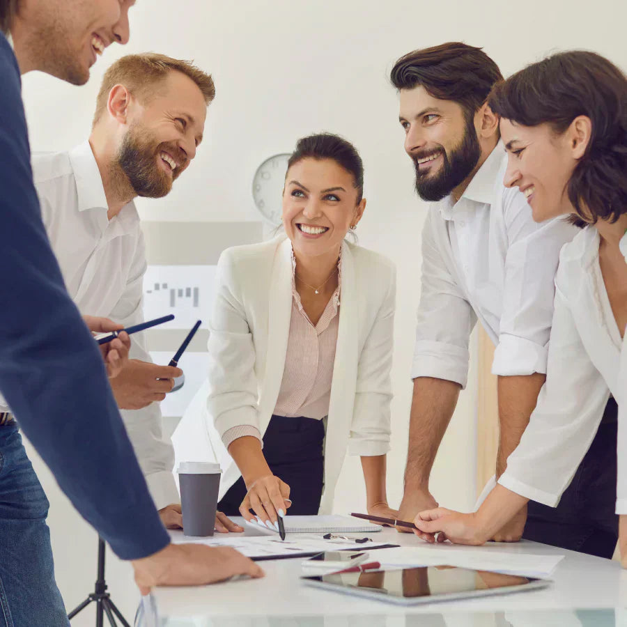 A smiling team of professionals collaborating during a meeting with a Plaud AI voice recorder on the table.