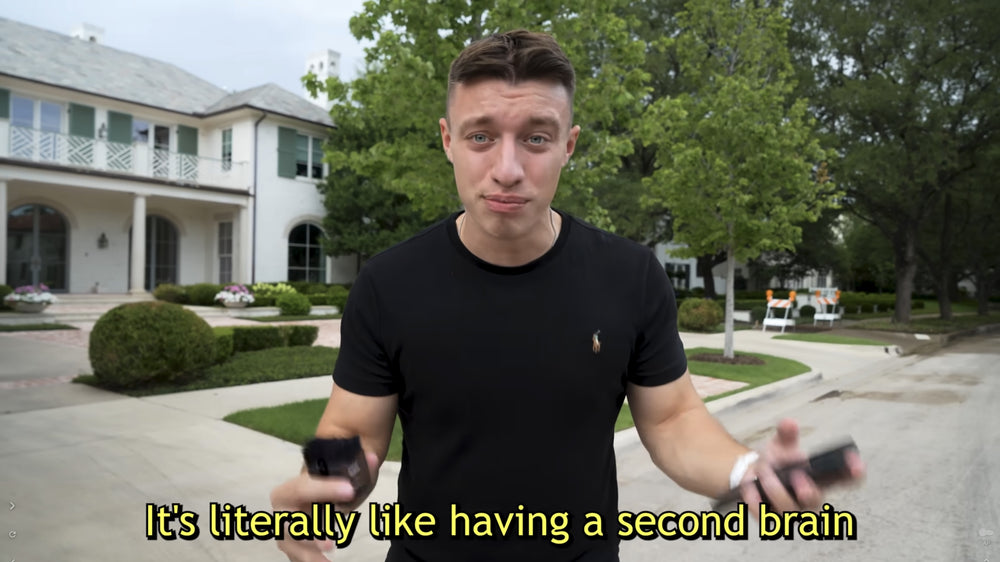 Man holding a black Plaud Note outdoors. Text: It's literally like having a second brain.