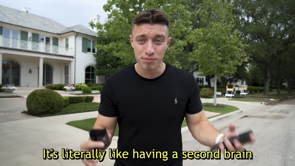 Man holding a black Plaud Note outdoors with text: It's literally like having a second brain.