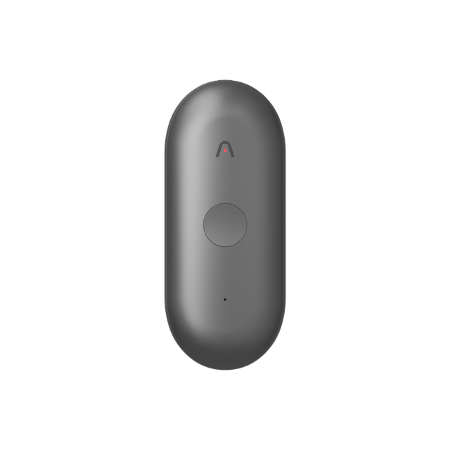 A dark grey Plaud NotePin S wearable AI recorder featuring a central round button and a small chevron logo.