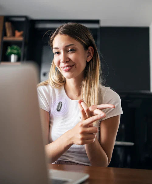 A woman wearing a black Plaud NotePin on her shirt while gesturing during a video call on her laptop.