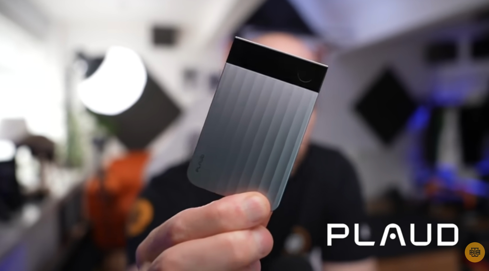 A hand holds a silver Plaud Note Pro AI voice recorder, highlighting its ribbed texture and top display screen.