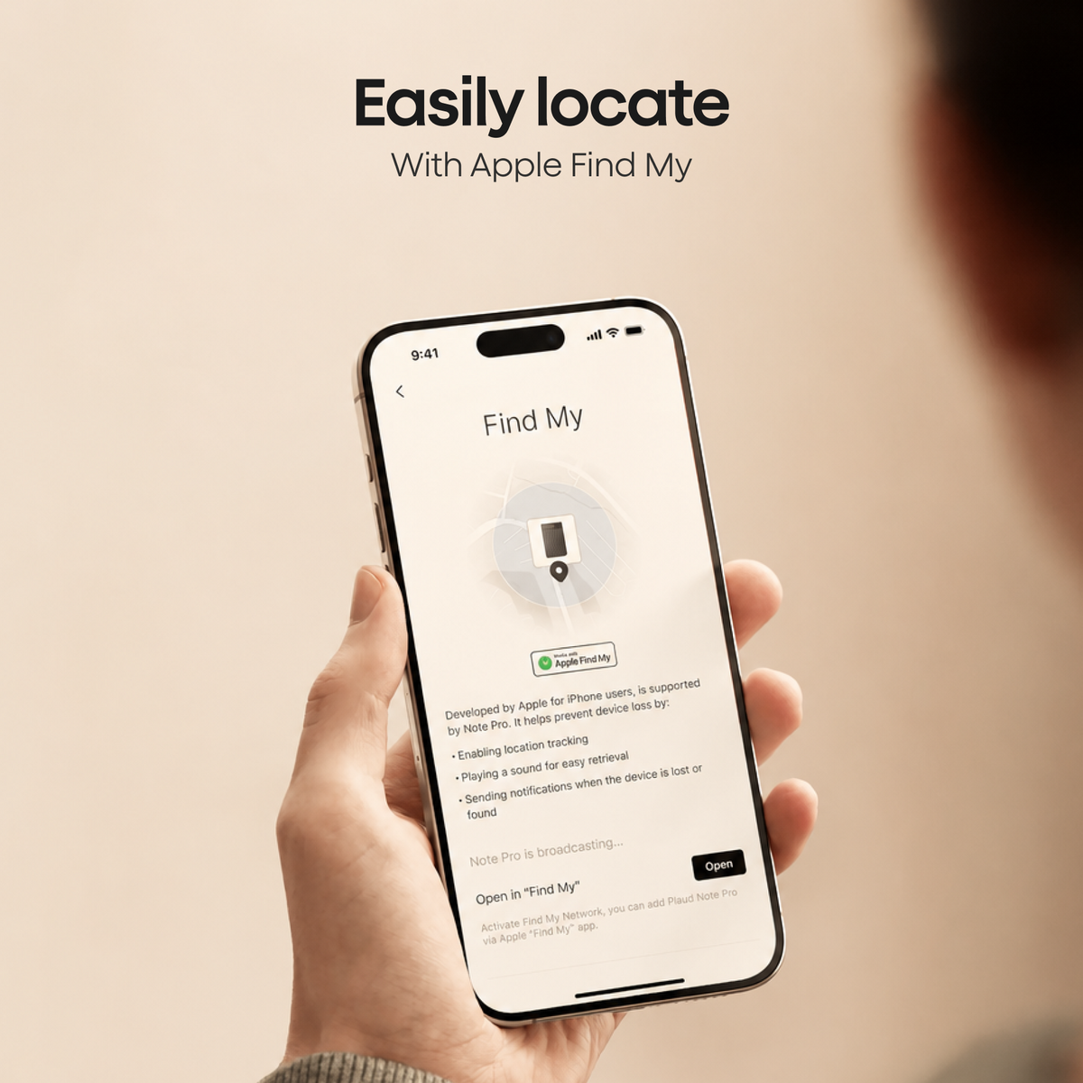 A person holds a smartphone displaying the Apple Find My app interface to locate a Plaud Note Pro.
