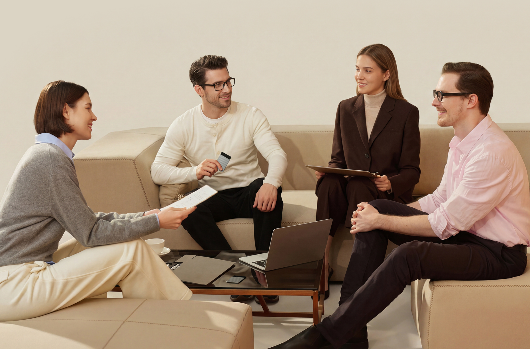 Four professionals sit on a beige sofa during a meeting, while one man holds a silver Plaud Note Pro AI voice recorder.